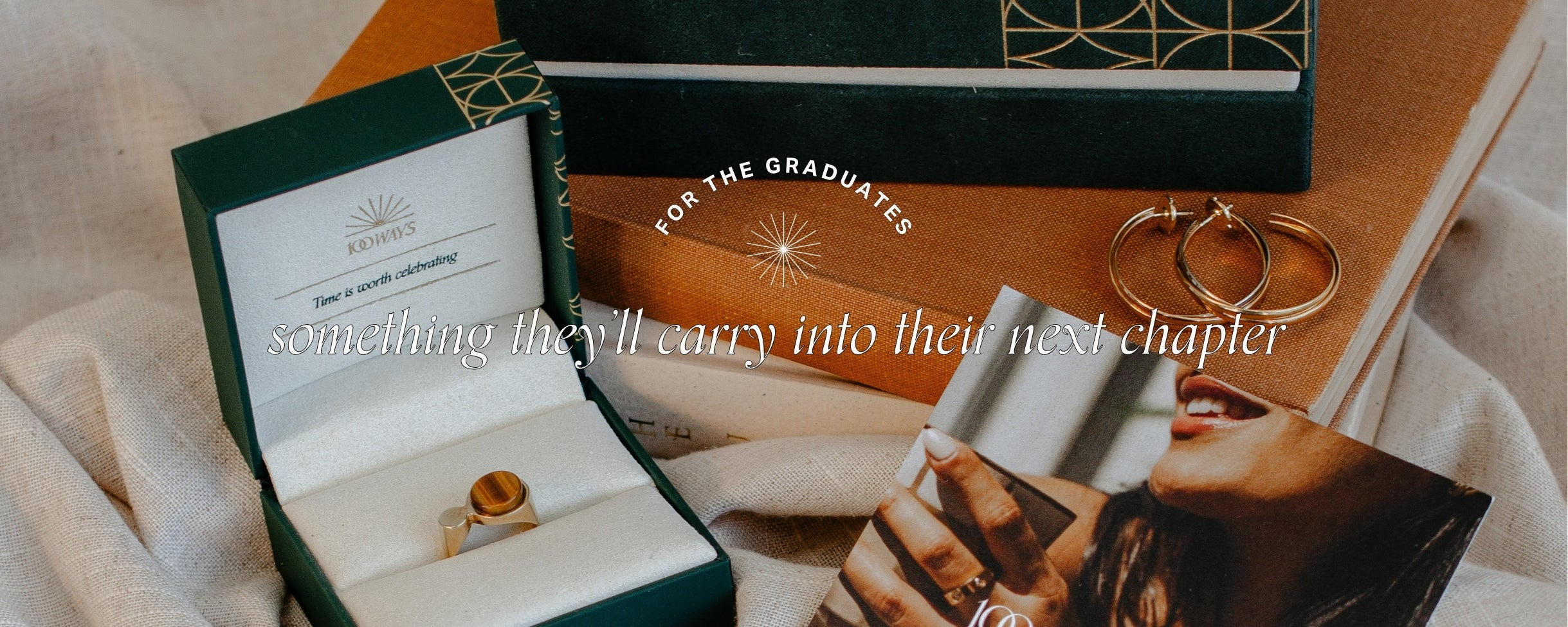 Image of jewelry boxes stacked on top of vintage, brown book and preloved, sustainable yellow gold jewelry. Text reads: For the graduates. Something they'll carry into their next chapter