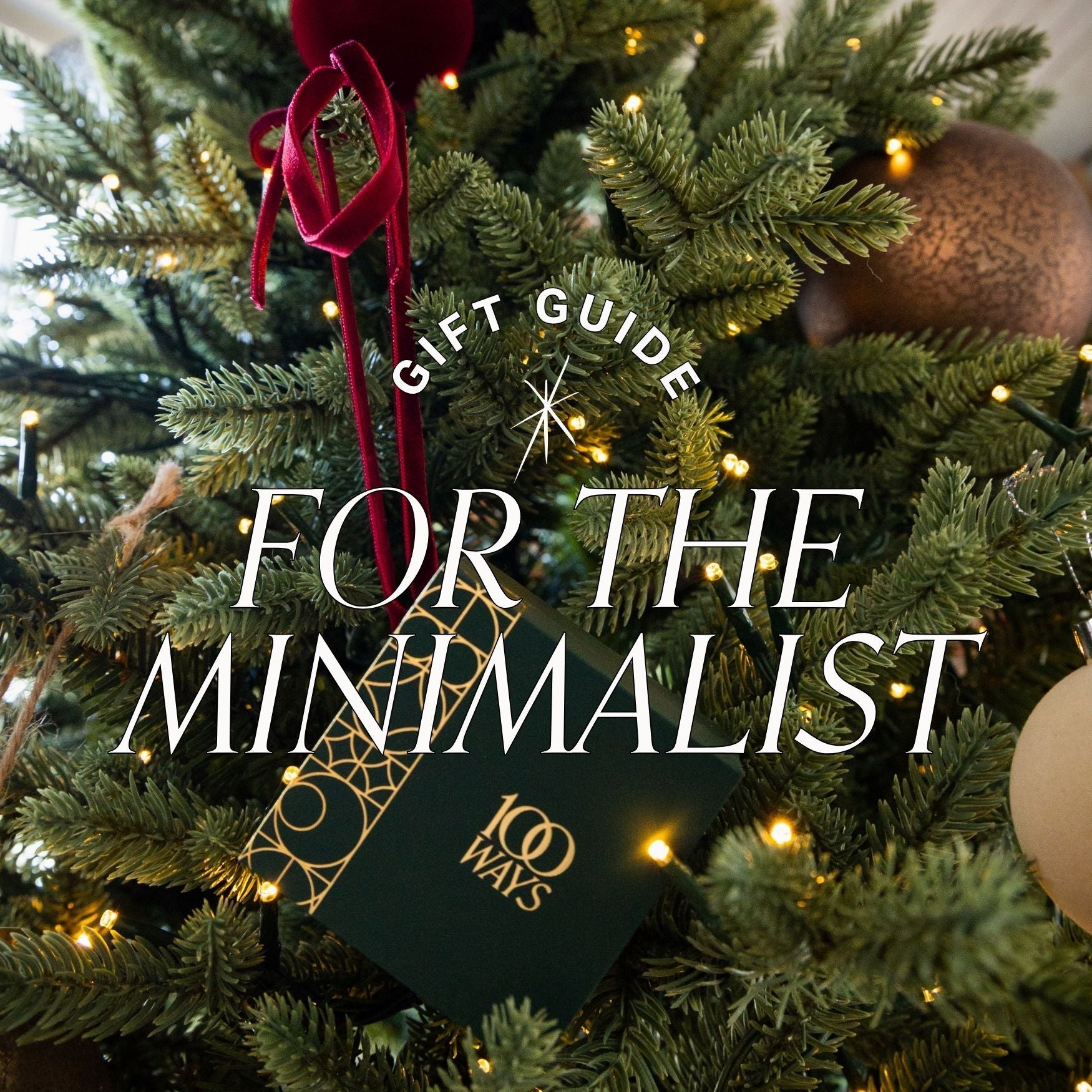 Hand hanging a 100 ways jewellery box on a decorated Christmas tree with 'Gift Guide for the Minimalist' text overlay