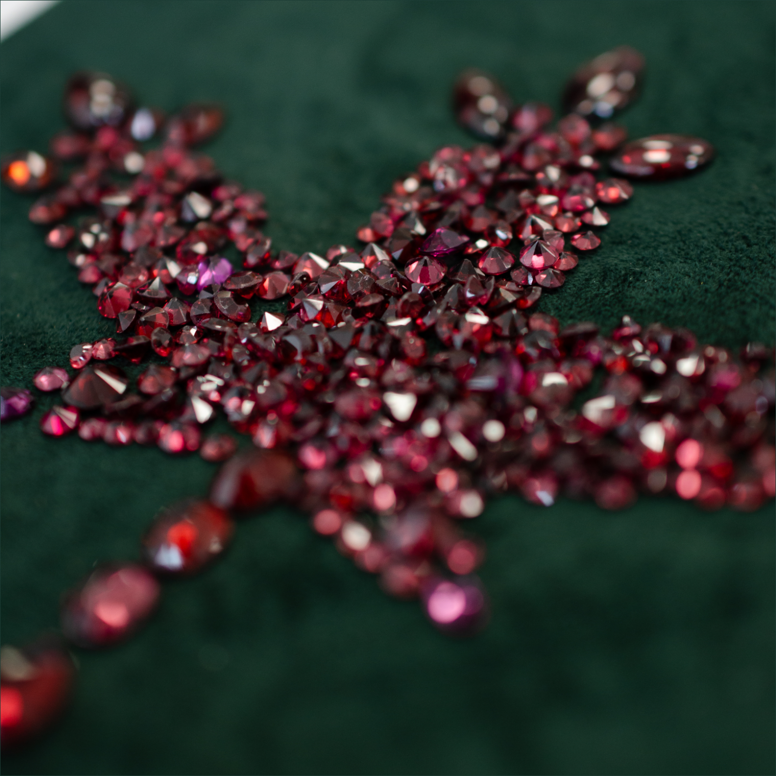 Assortment of rubies and garnet gemstones arranged in a maple leaf shape