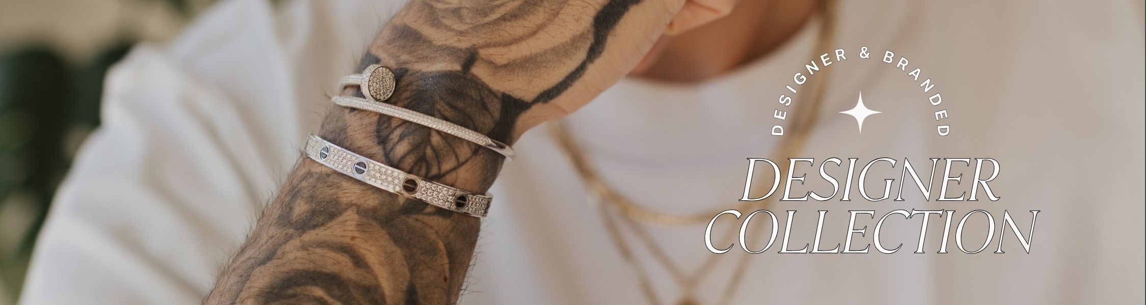Close-up of a tattooed arm with brand name designer bracelets, blurred background with text overlay: 'Designer & Branded collection'.