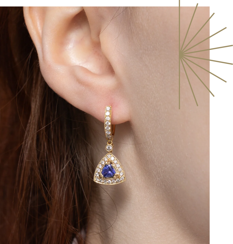 Gold tanzanite drop earrings on ear. December birthstone jewellery with vintage diamond halo.
