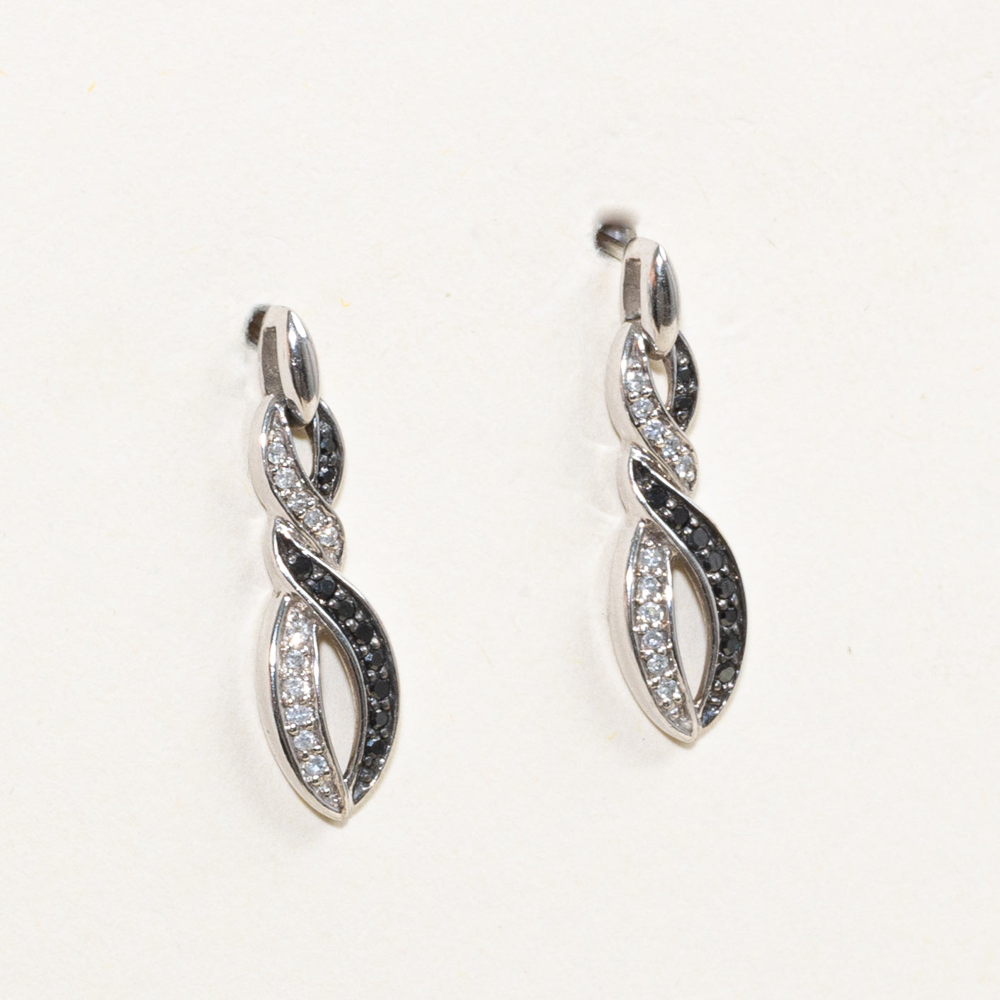 Boucles d'oreilles pendantes croisées serties de diamants noirs et blancs pavés