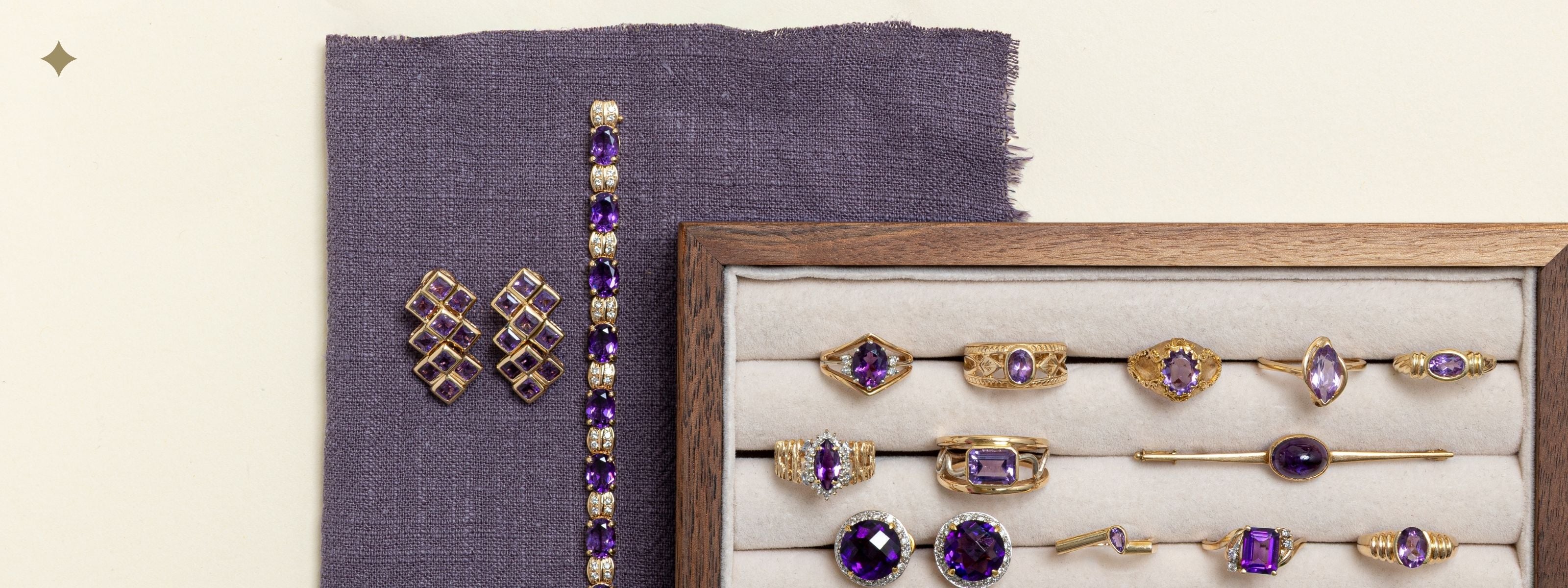 Vintage gold rings and brooches with deep purple amethyst gemstones displayed in a velvet jewellery tray, part of a February birthstone collection.