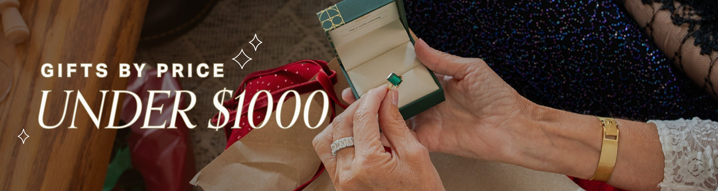 Person holding a small gift box with a ring, surrounded by festive decorations. Text over reads gifts by price, under $1000