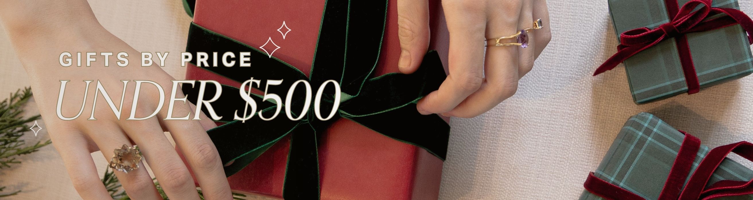 Gifts by price under $500 with hands holding a wrapped gift and another gift in the background.