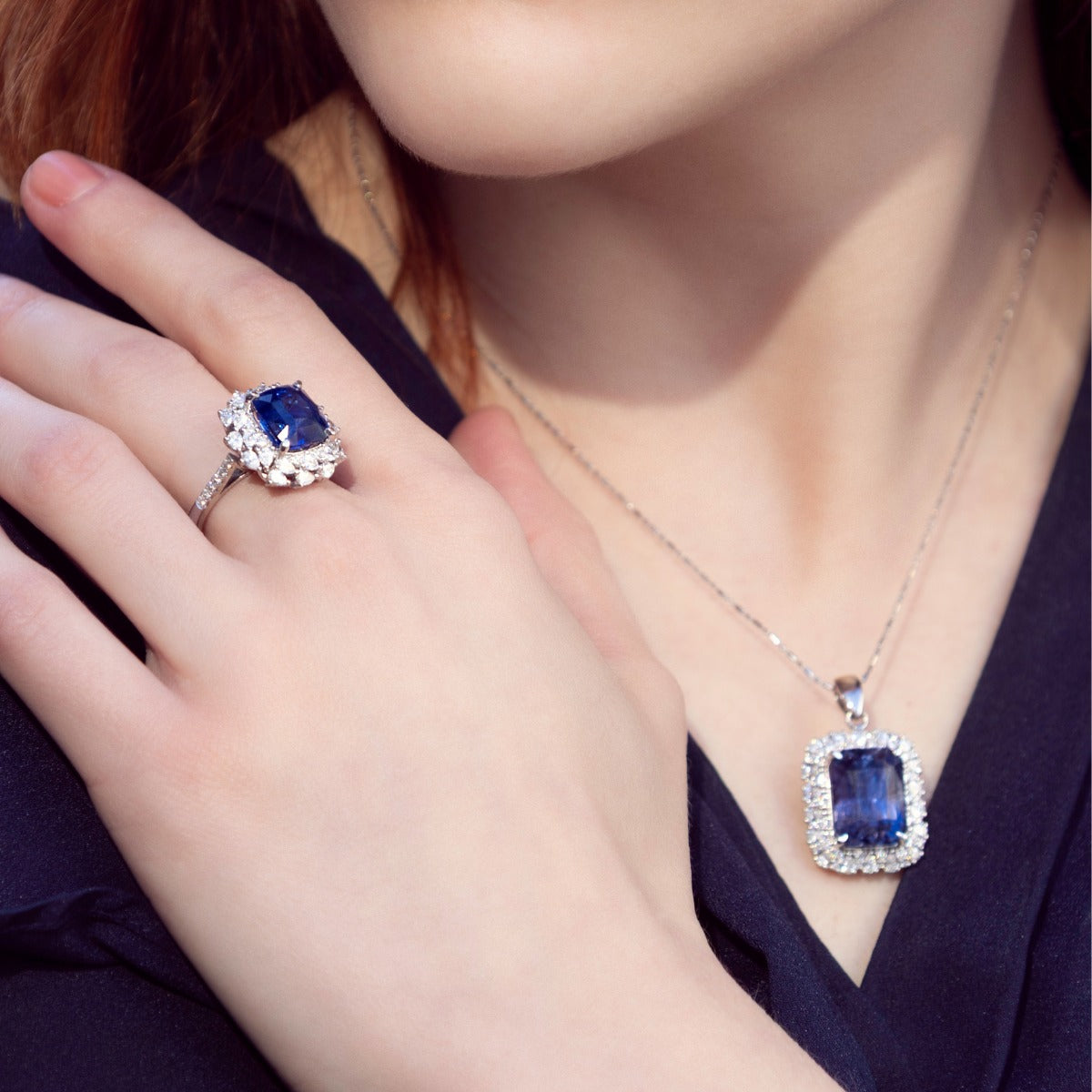 Model wearing high jewellery ceylon sapphire and diamond halo ring with matching sapphire pendant in white gold