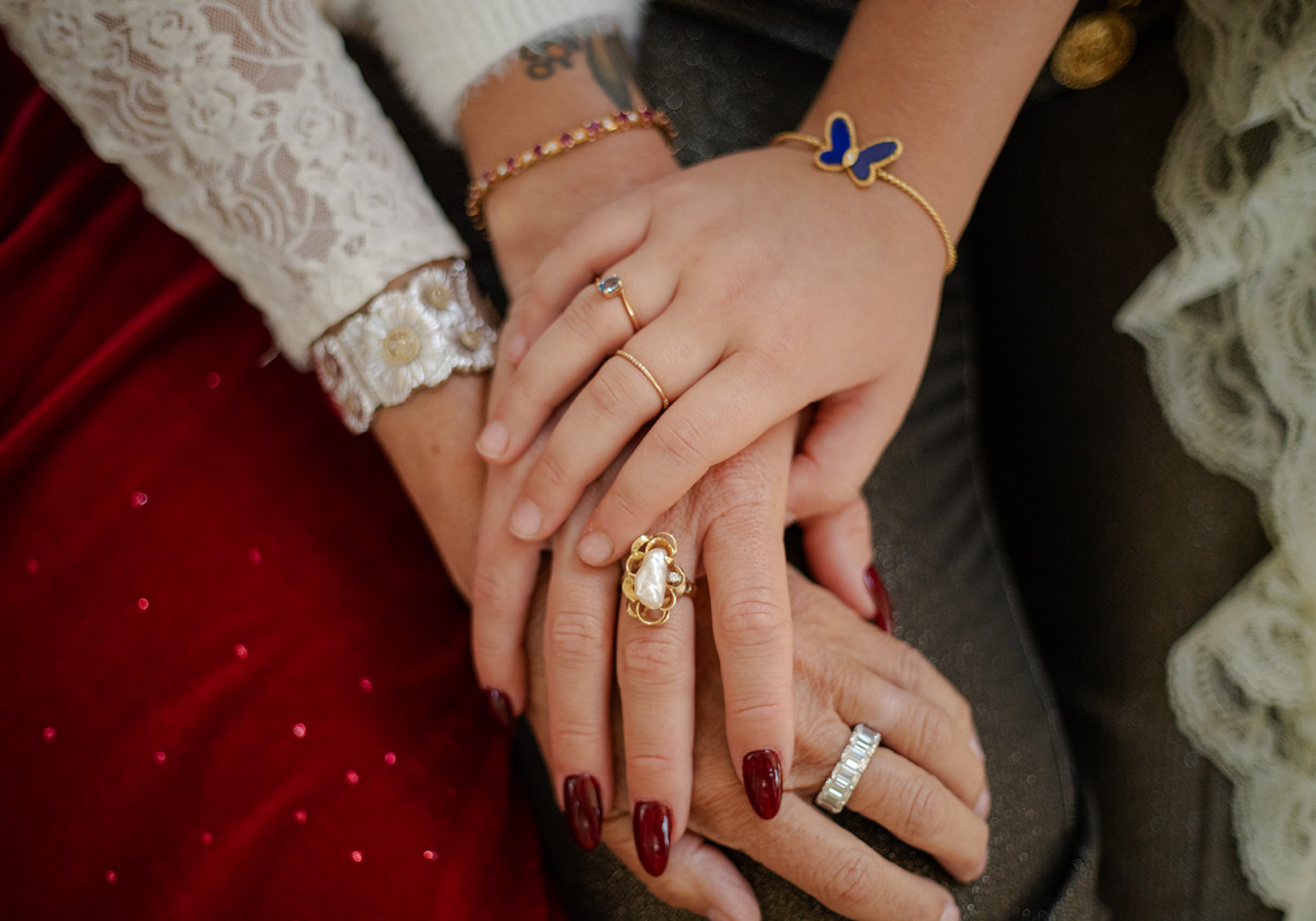 Close-up of intertwined hands adorned with vintage and preloved jewellery, including gold rings, a pearl baroque statement ring, and designer, delicate bracelets.