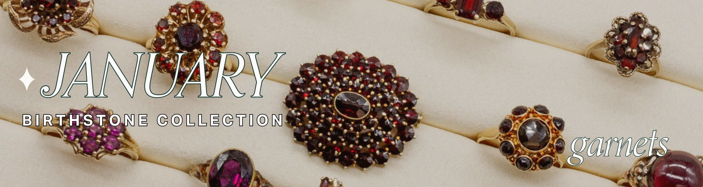 Garnet jewelry collection with 'January Birthstone Collection' text on a beige jewellery tray holding garnet vintage rings.