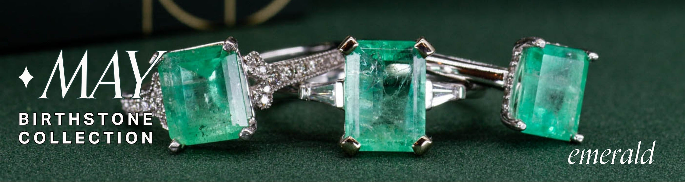 image of three emerald and white gold rings with diamond accents on green background. text overlay reads: may birthstone collection, emerald