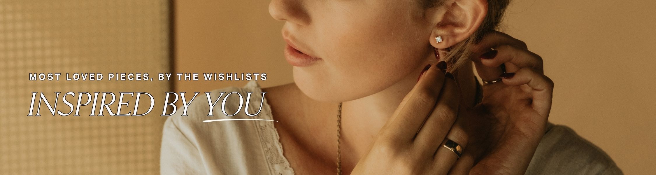 Person adjusting an earring with a warm, beige background and text overlay that reads: most loved pieces, by the wishlists... inspired by you