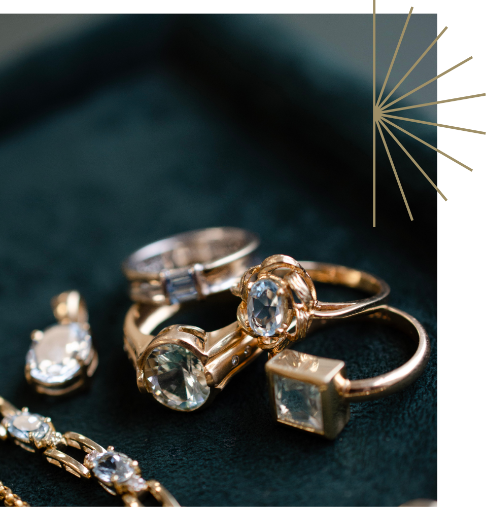 Collection of aquamarine rings in yellow gold settings styled together on a dark green velvet tray.
