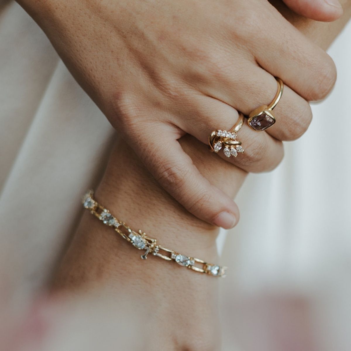 March birthstone aquamarine bracelet in yellow gold with pale blue stones, worn alongside fine, vintage rings.