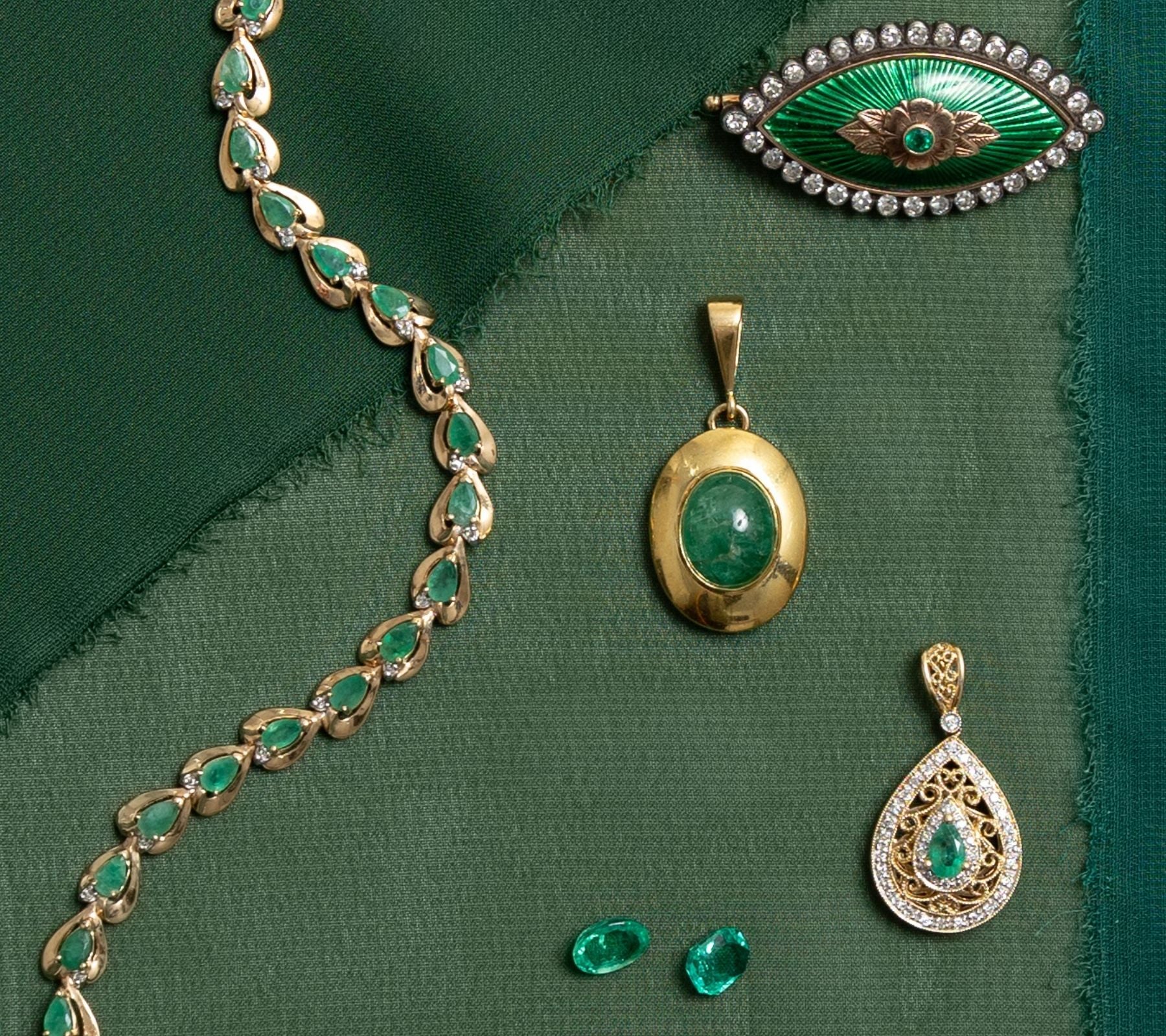 Selection of vintage emerald jewelry, including a teardrop emerald and diamond, simple chunky emerald pendant, teardrop emerald bracelet and a detailed green enamel antique brooch.