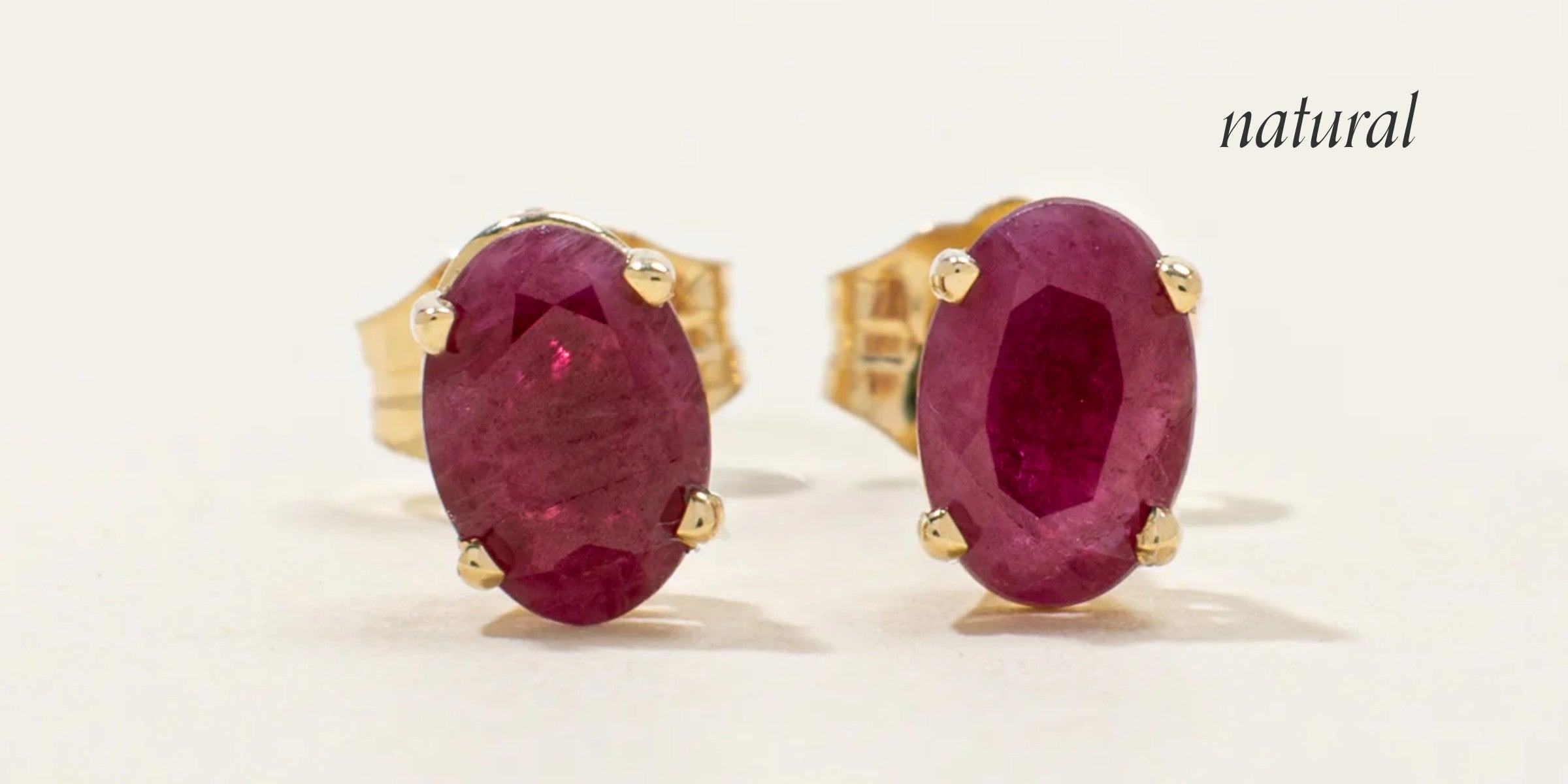 Vintage yellow gold stud earrings featuring genuine oval-cut natural rubies with visible inclusions, showcasing the characteristic look of authentic ruby gemstones.