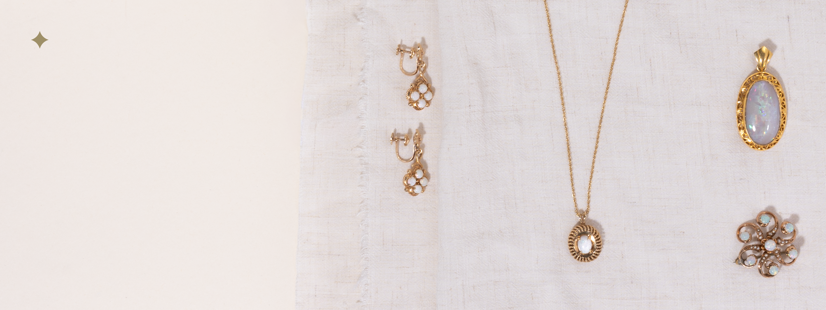 Flat lay of vintage opal jewelry, including gold earrings, a pendant necklace, and several brooches and pendant, styled on soft linen fabric.