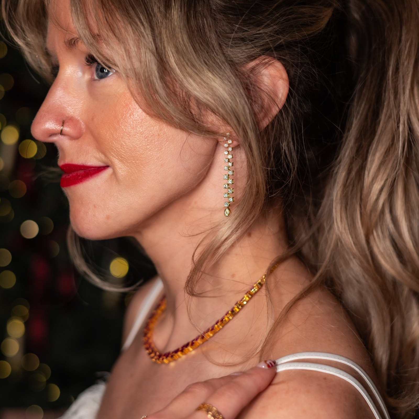 Woman wearing vintage gold and diamond drop earrings and ruby necklace, styled with red lipstick — preloved fine jewellery styled for special holiday occasions.