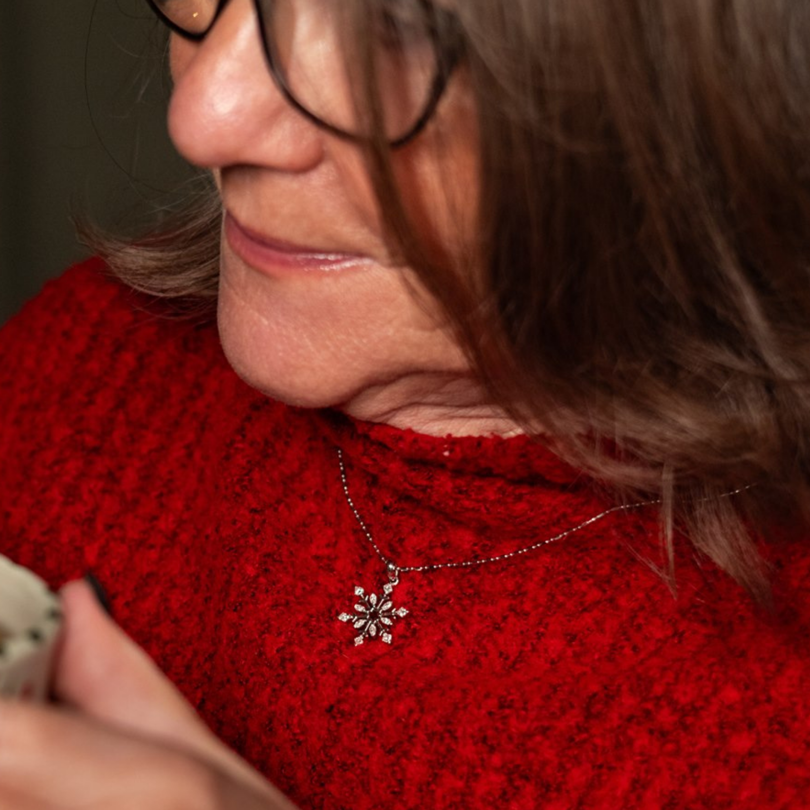Woman in a red sweater wearing a white gold, snowflake diamond pendant — vintage-inspired necklace capturing festive nostalgia and timeless style.