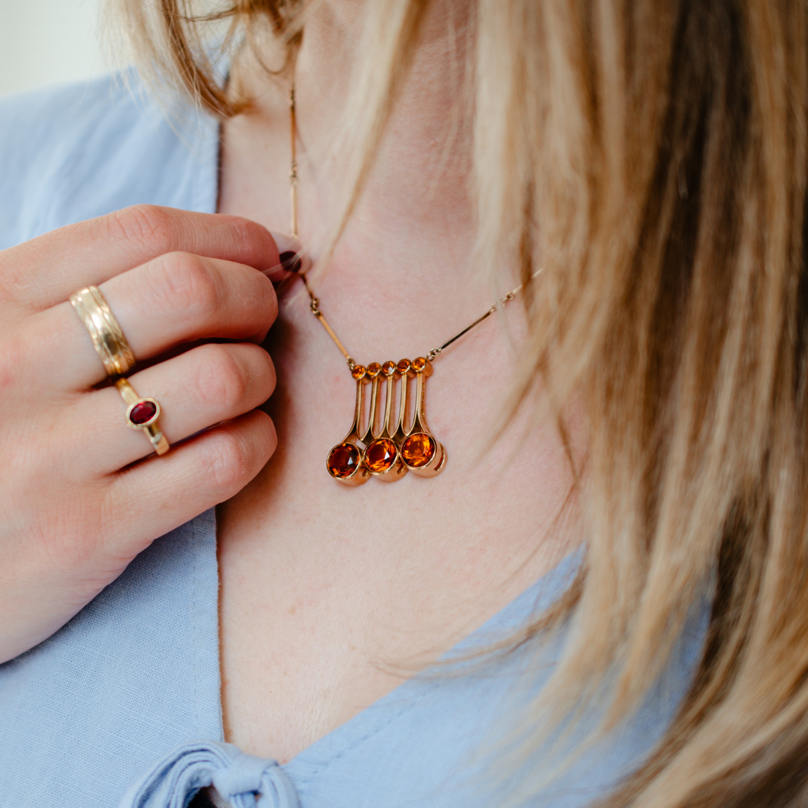 Model wearing a midcentury style citrine pendant necklace with minimal vintage, yellow gold rings
