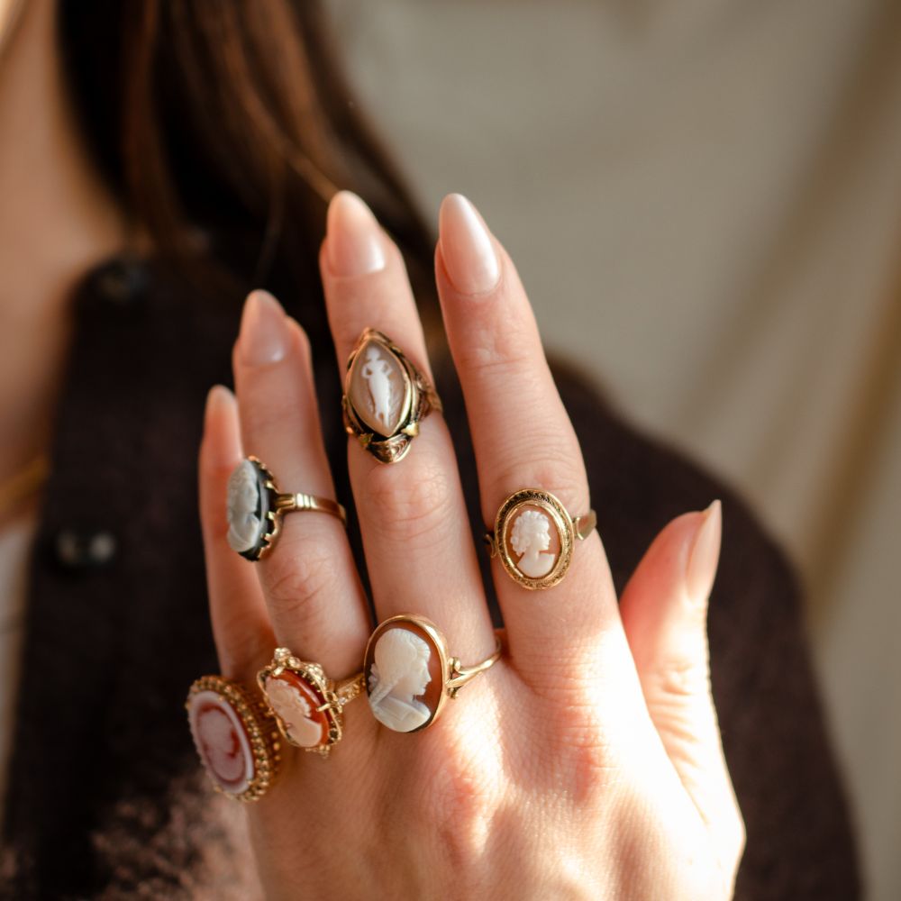 Model wearing multiple antique cameo rings of various styles and sizes featuring hand carved portraits of women