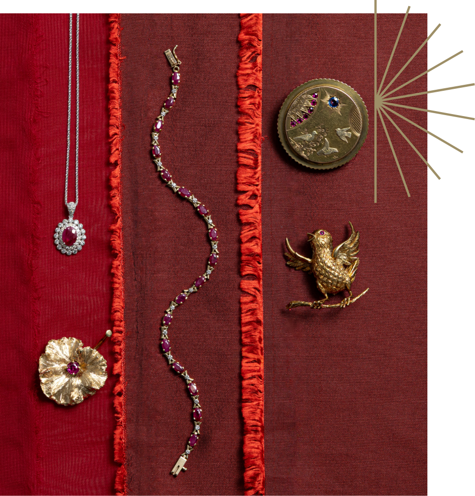 Flat lay of preloved, fine jewelry with a gold starburst graphic, featuring an assortment of ruby jewellery: vintage ruby halo pendant, a gold bird pin, and a textured gold flower pendant.