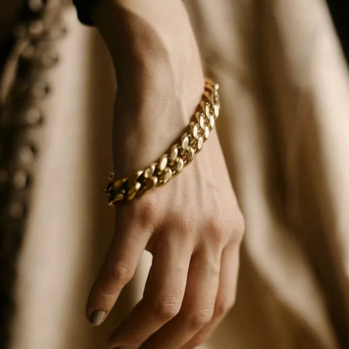 close up image of woman's hand by her side with oversized chain link gold bracelet