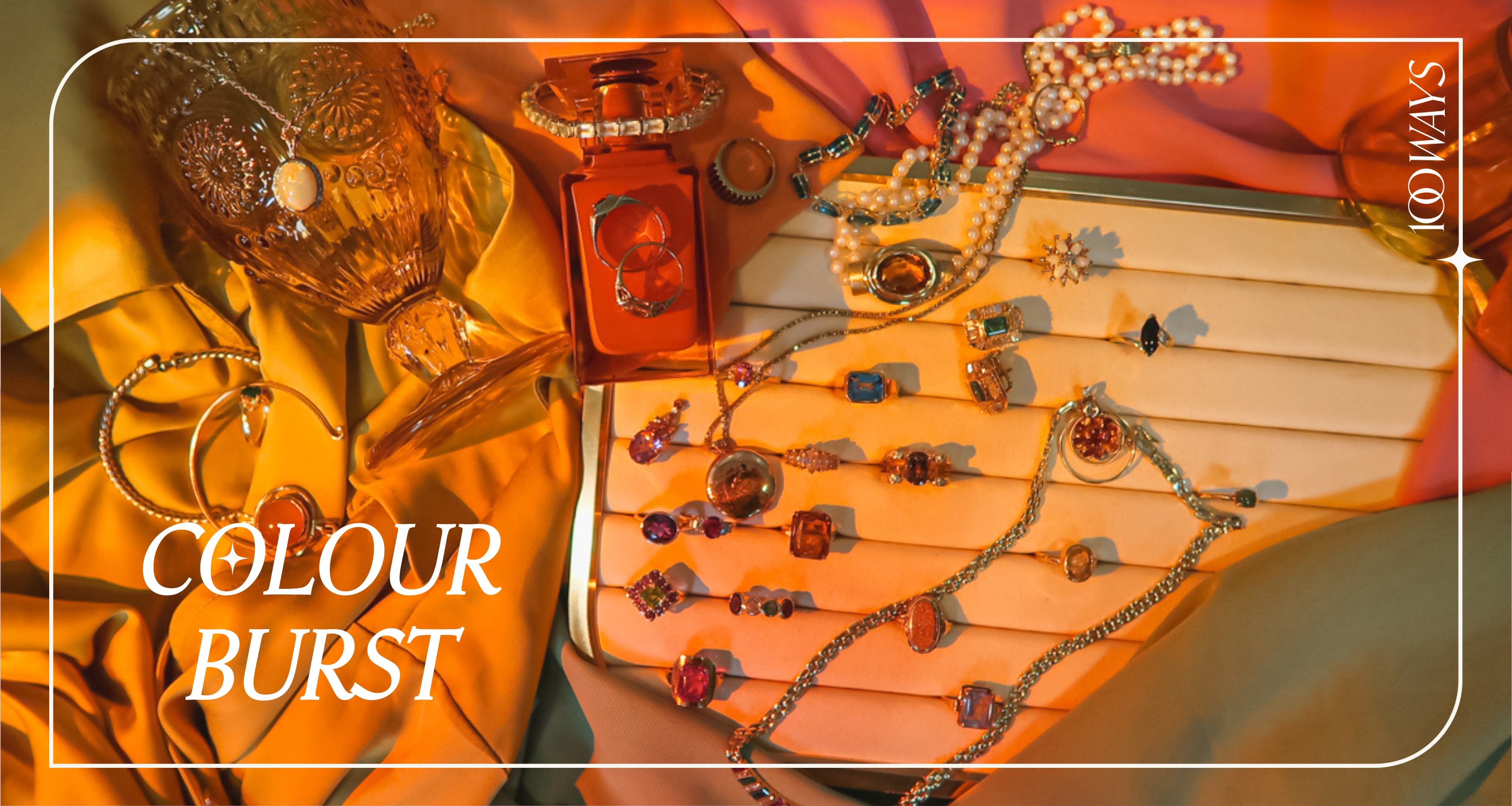 colourful gemstone jewellery on a velvet tray in golden rainbow light surrounded by jewel toned props. text over reads 'colour burst'