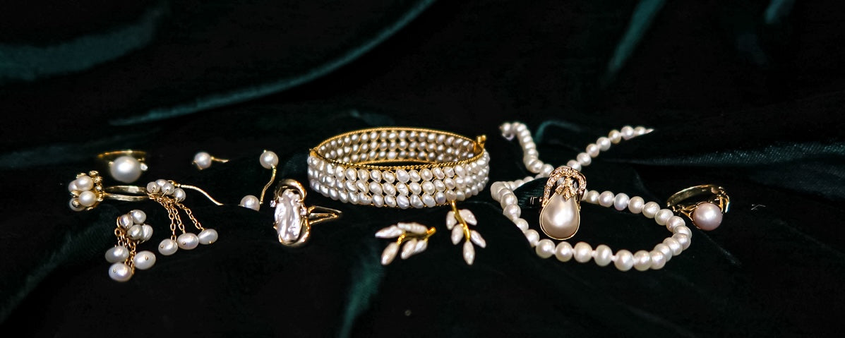pearl jewellery on green image of assorted pearl jewellery with yellow gold details on dark green velvet