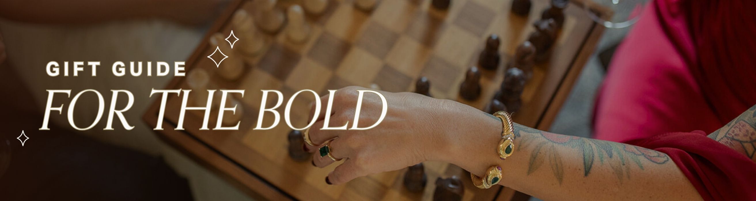 Hand with gold bracelet on a checkered surface, with text 'Gift Guide for the Bold'.