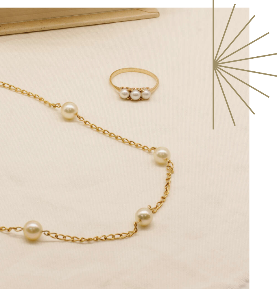 vintage gold pearl chain and three stone ring on textured fabric