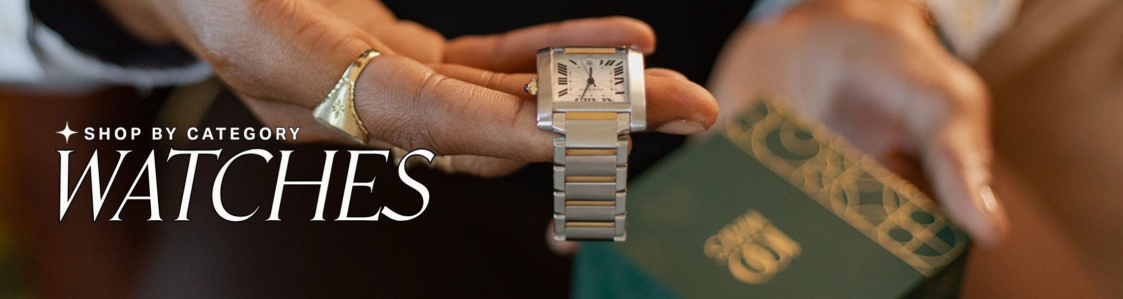 Hand holding a silver watch with blurred background, Text over reads: shop by category: watches