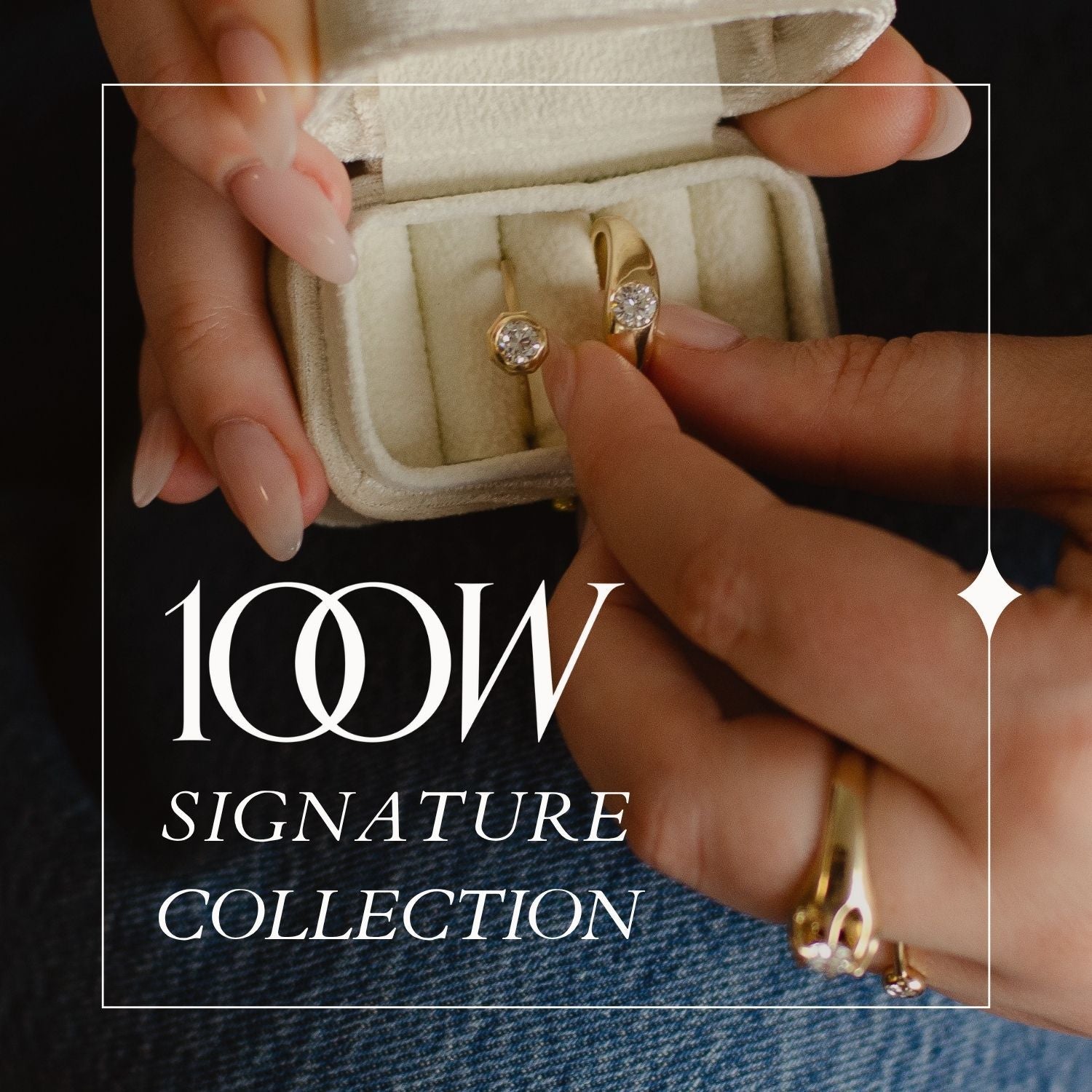 woman wearing jeans and black long sleeve shown holding small jewellery box with modern gold rings and brilliant diamonds made from reclaimed materials; text overlay reads 100W Signature Collection