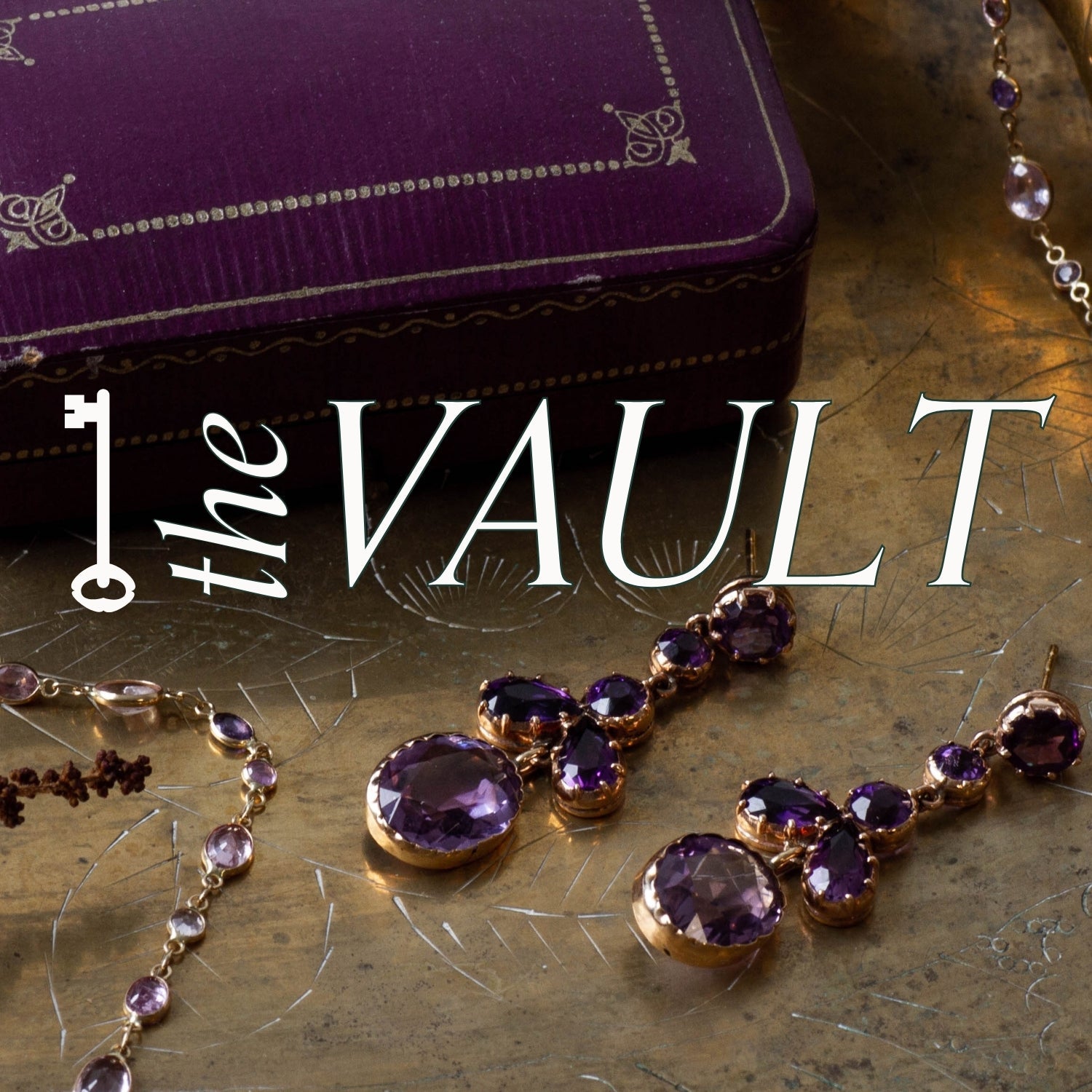unique amethyst drop earrings and bezel set necklace on gold jewellery tray with dried florals. Overlay of 'The Vault' branding  and a key graphic. subtitle text reads: a hand curated collection of note-worthy jewellery