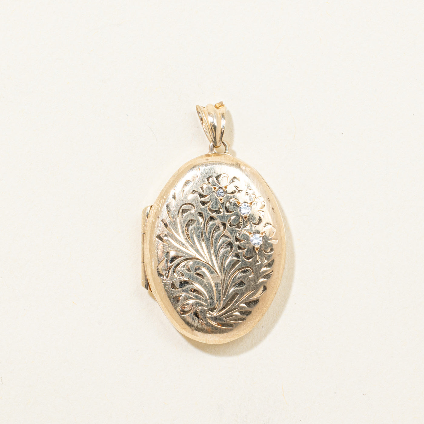 Gold and silver locket with intricate design on a white background