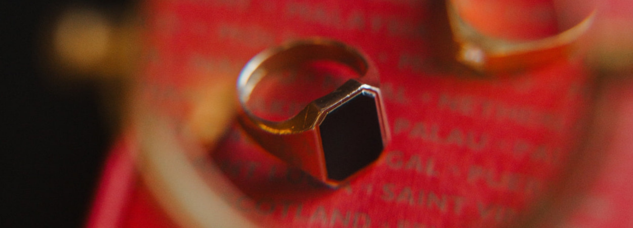 A second-hand luxury yellow old and onyx statement ring, captured through a magnifying glass over an antique book.