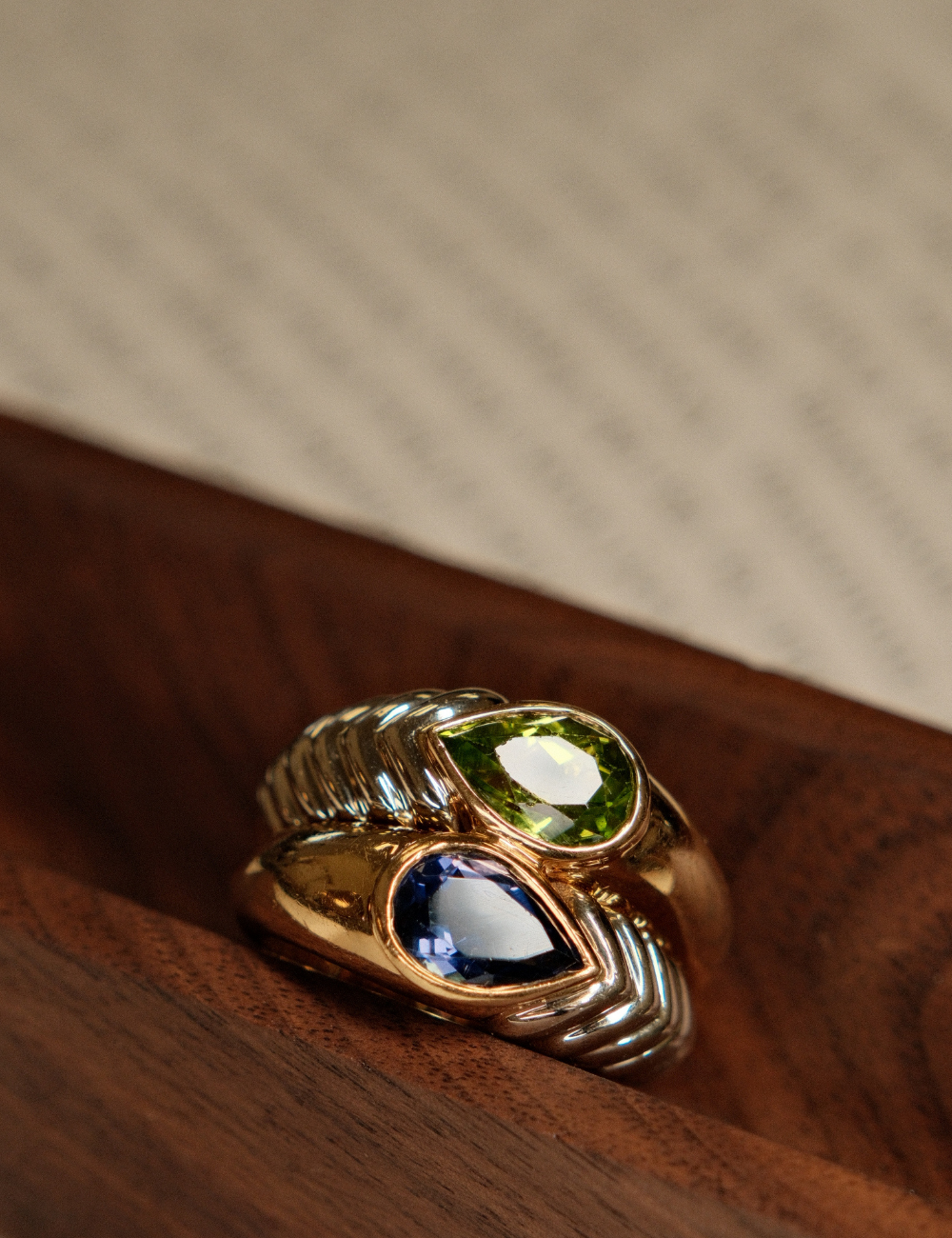 Close-up of a preowned Bvlgari Iolite & Peridot Doppio Ring, resting on a wooden jewelry tray.