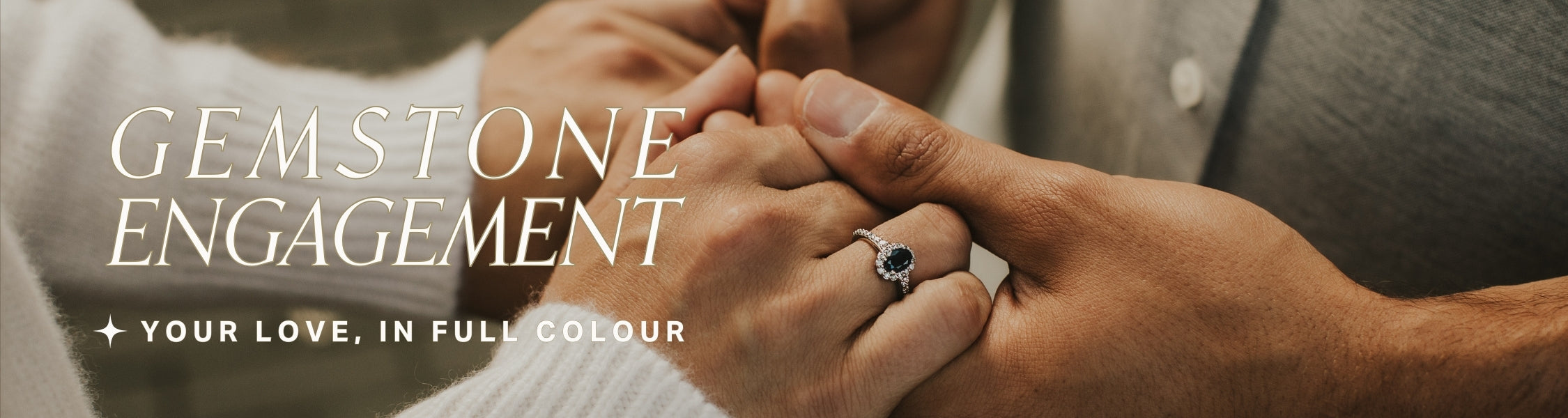 Close-up of hands with a sapphire gemstone engagement ring, featuring text overlay: gemstone engagement: your love in full colour