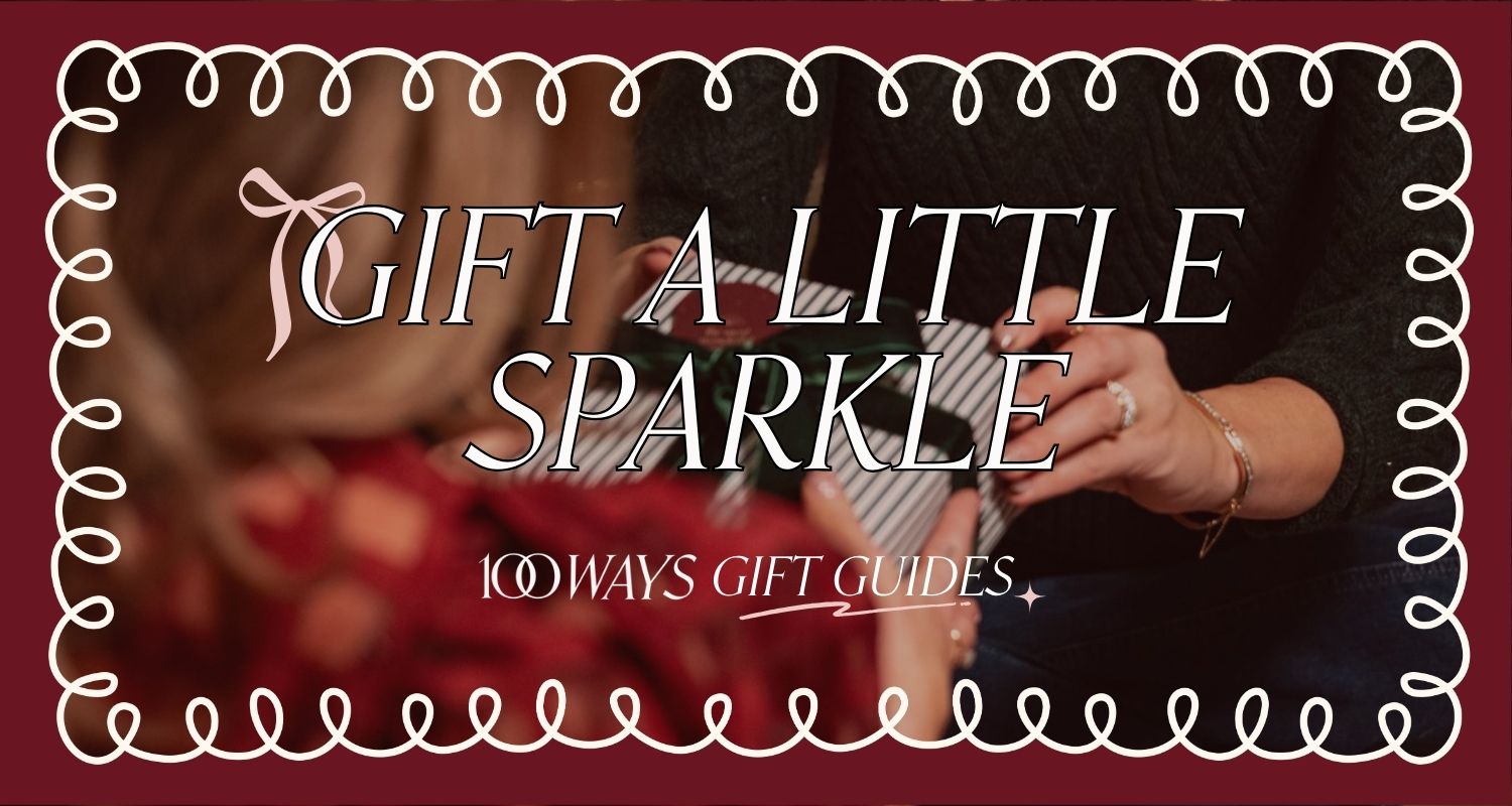 banner image of women exchanging gifts wearing fine gold jewelry. banner has loopy border and text reads 'gift a little sparkle: 100 Ways Gift Guides'