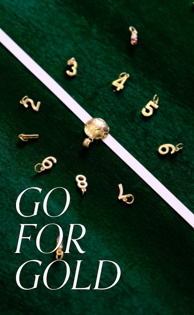 Yellow gold number pendant charms surrounding a yellow gold soccer ball charm, made from recycled gold, mimicking a soccer field. Text reads: Go for Gold