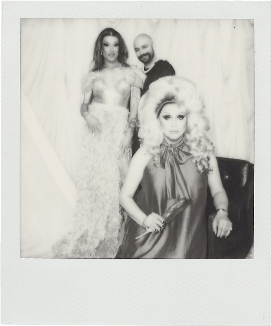 Black and white Polaroid-style photo of three LGBTQ2S+ community members, Kendall Gender, Evan Clayton, Jaylene Tyme, styled in vintage glam and jewelry for Vancouver Pride 2025. A nostalgic tribute to celebrating pride and the community.