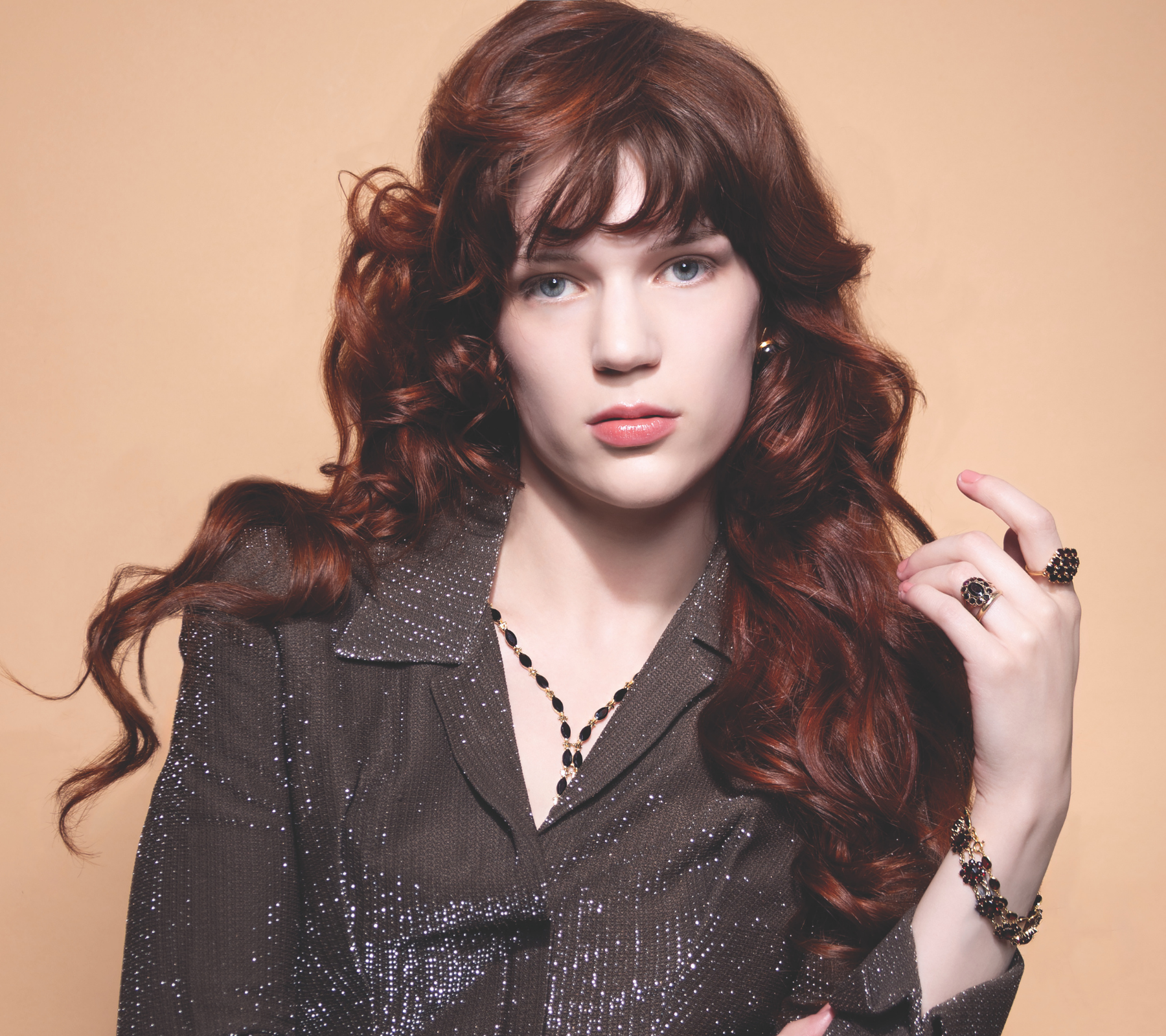 Model wearing vintage garnet jewellery, including gold garnet rings, stacking bracelets with deep red gemstones.