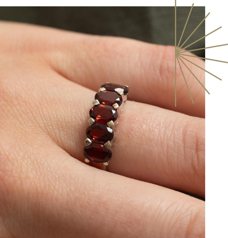 Close up detail of semi eternity, vintage, oval shaped garnet ring