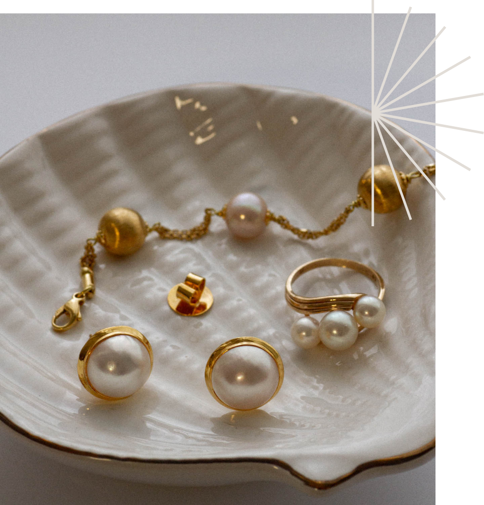 Modern, contemporary mabe pearl earring with three stone contemporary ring with yellow old pearl satelite bracelet in a ceramic shell tricket tray.