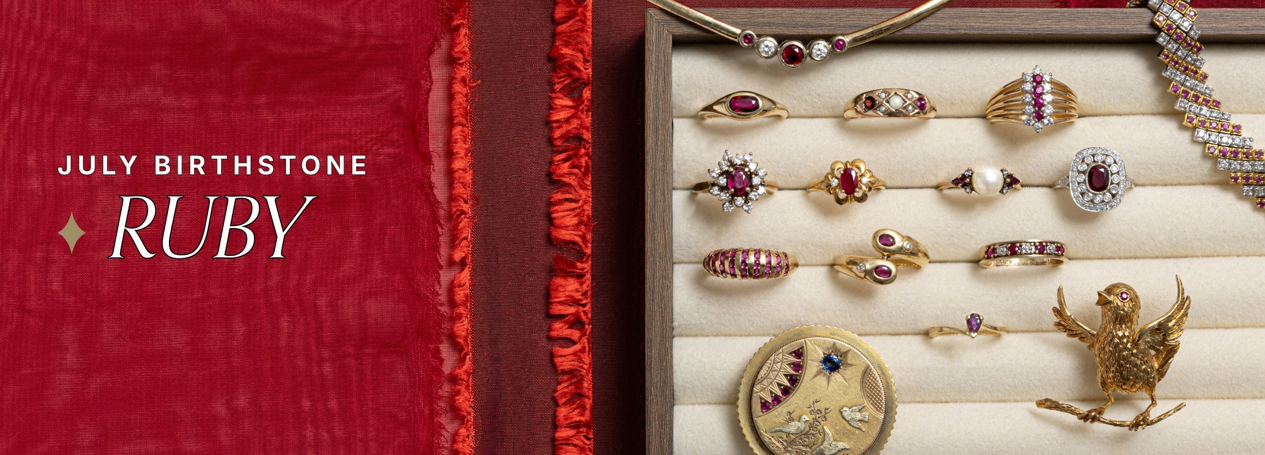 An array of preloved estate jewelry and vintage ruby rings on a walnut brown jewellery tray. Text reads: July birthstone, ruby.