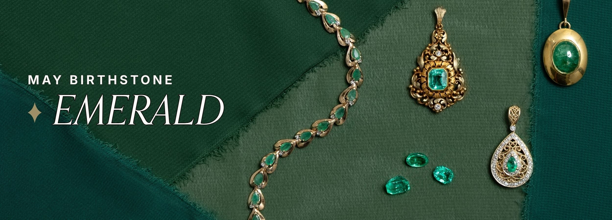 May birthstone emerald collection featuring antique gold necklaces, intricate pendants, and loose emerald gemstones displayed on rich green chiffon fabric. Text reads: May birthstone emerald.