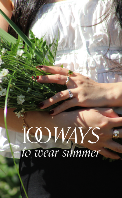A close-up lifestyle shot of a person outdoors holding a bouquet of white daisies, wearing a white ruffled top and multiple vintage diamond and gemstone rings. Text reads: 100 Ways to Wear Summer