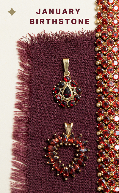 Vintage garnet jewellery laid on burgundy fabric, featuring gold garnet bracelet  and pendants in deep red tones. Text reads: January birthstone