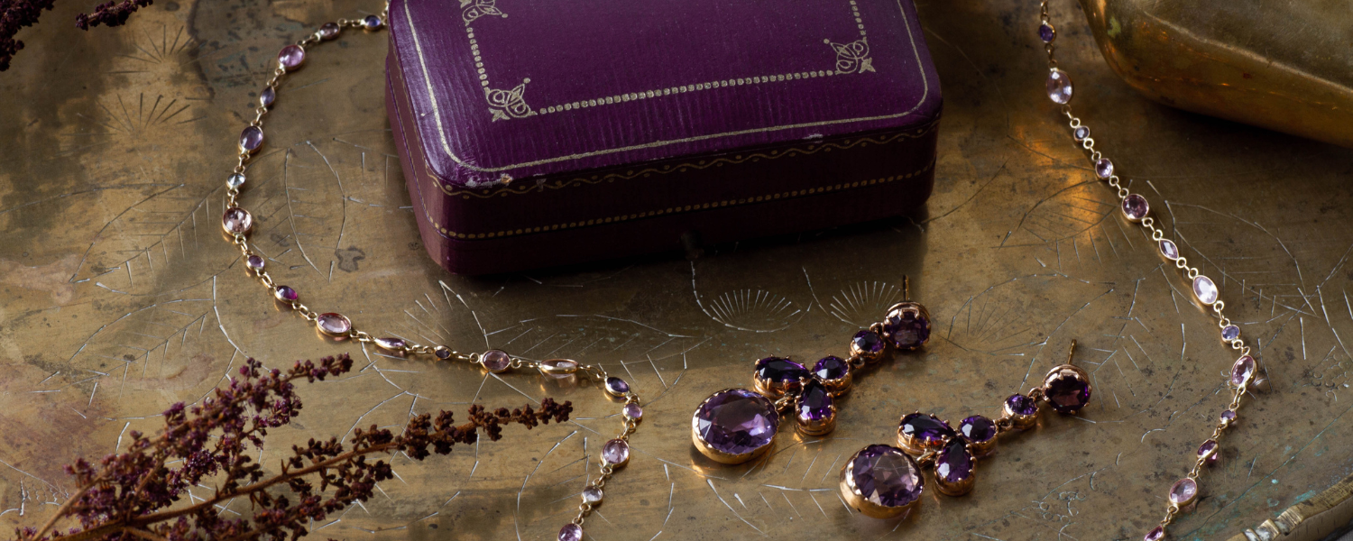 Amethyst, vintage yellow gold necklace and drop earrings styled on patterned gold tray and antique jewelry box