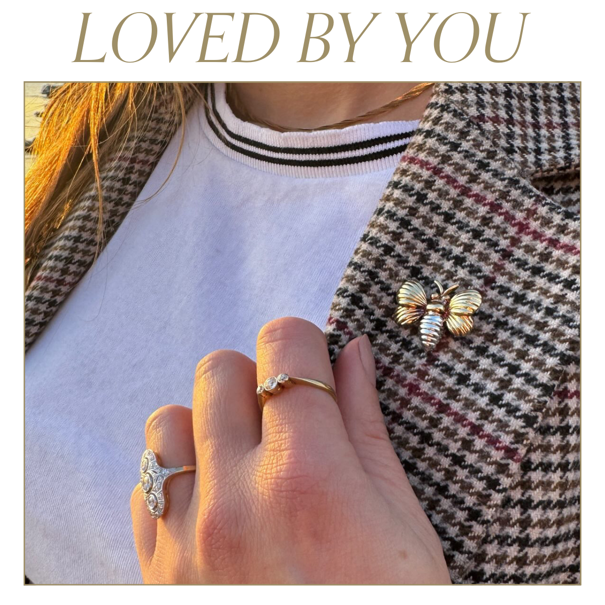 Model wearing houndstooth blazer and simple white t-shirt wearing yellow gold bee brooch, and Art deco inspired white gold ring. Text reads: Loved by you