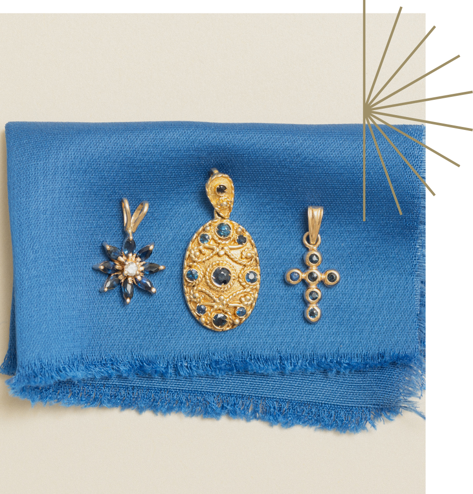 Three gold, vintage, unique yellow gold sapphire pendants on a satin blue fabric