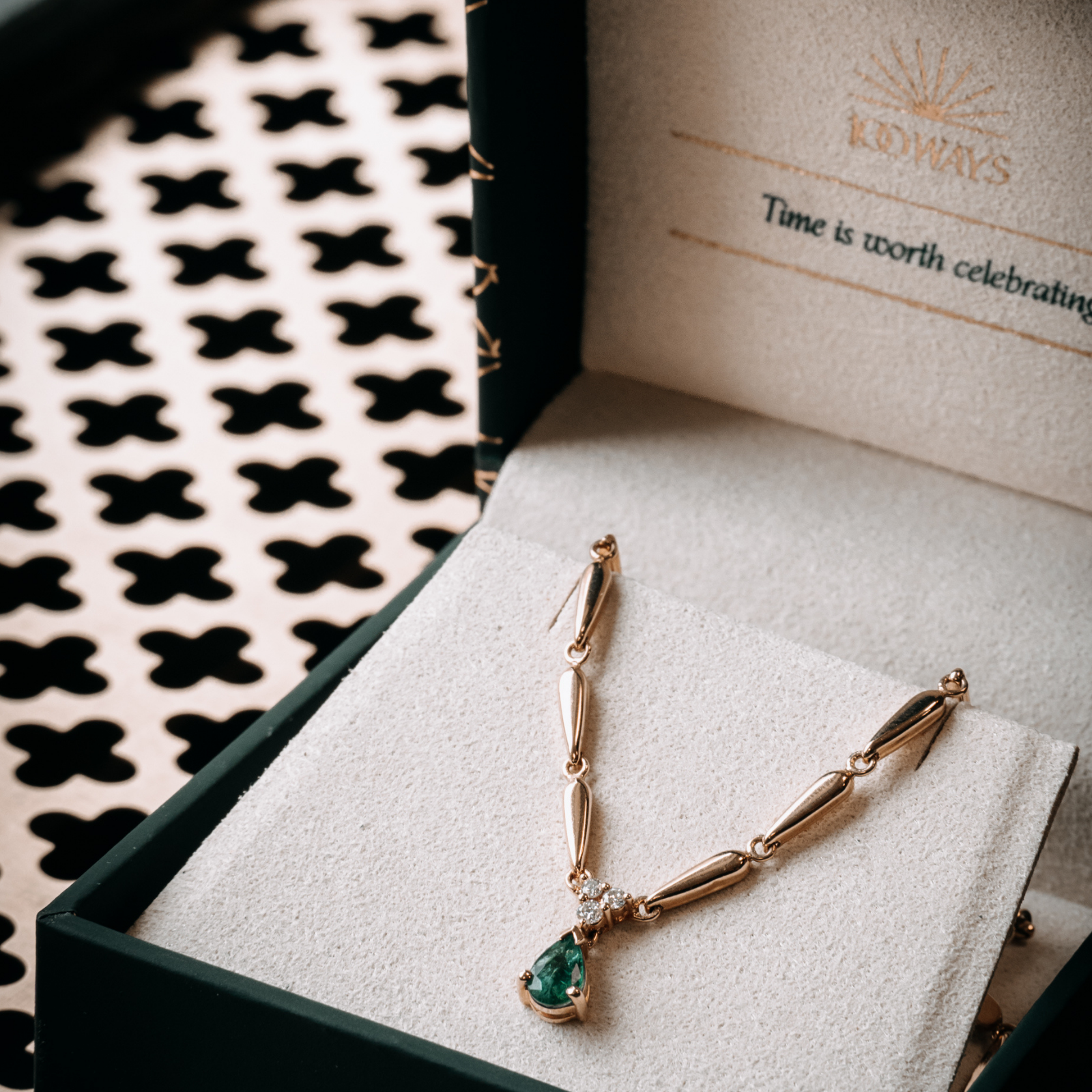 Vintage gold necklace featuring a pear-cut emerald and diamond pendant, beautifully presented in a green 100 Ways jewellery box. 